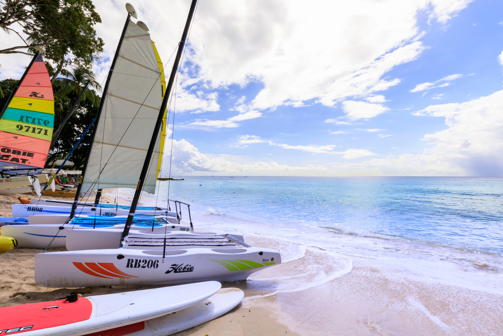 Ashore sailboats and a calm beach during a cloudy mid day in St. James, one of the best areas to stay in Barbados.