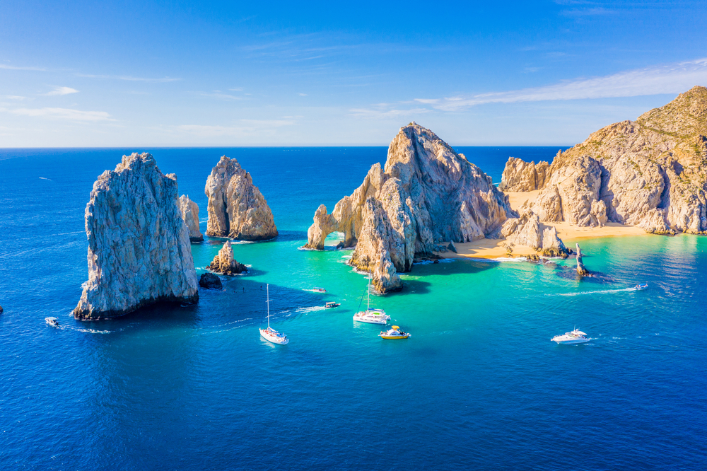 Aerial view of El Arco, the Arch, with boats in the blue water around it for a list of the best all-inclusive resorts for families in Cabo San Lucas