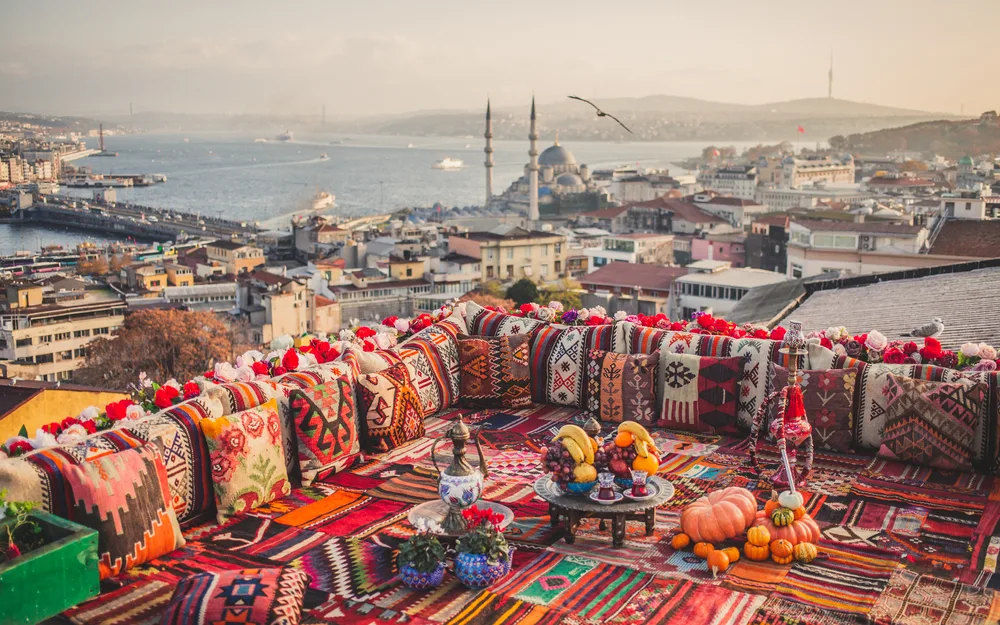 Panoramic view of the town of Istanbul pictured with lots of colorful and ornamental pillow in the foreground pictured for a guide titled Is Istanbul Safe to Visit