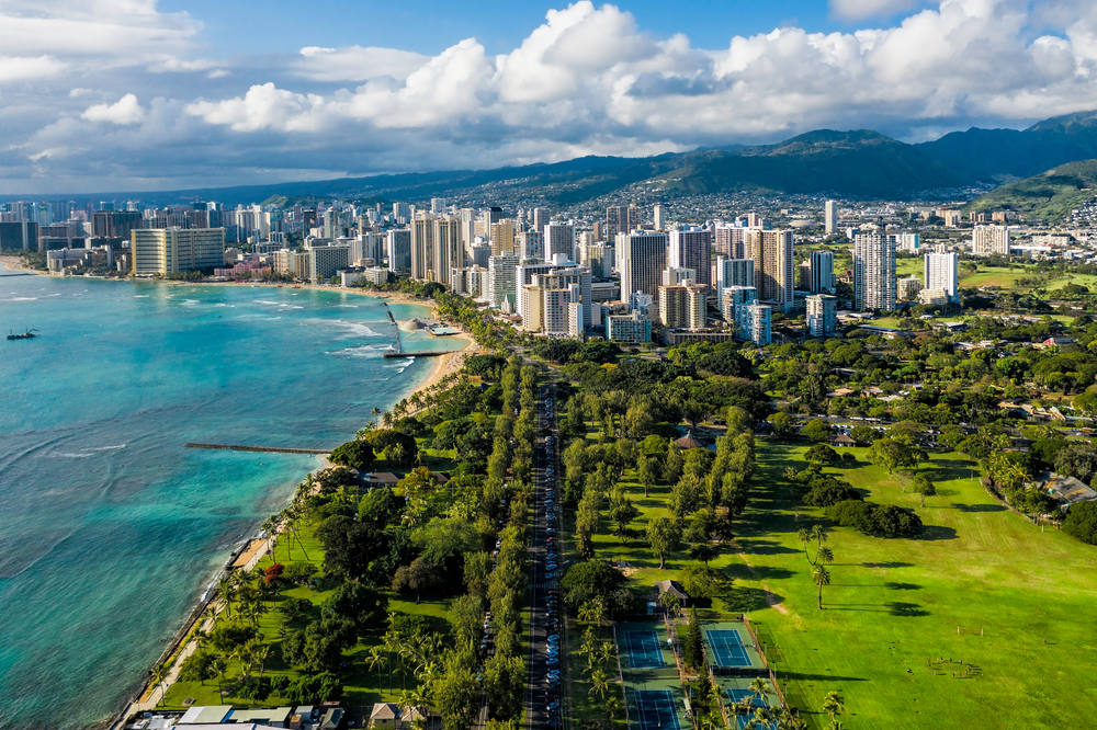 Aerial view of the shore of Waikiki on Oahu, Hawaii during winter with fluffy clouds and blue skies overhead 