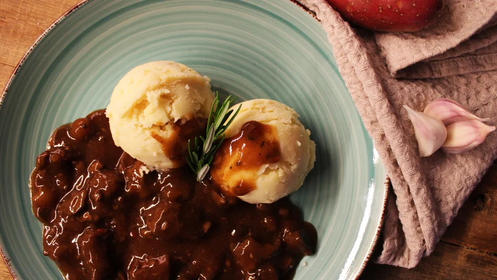 Hachee beef and onion stew with mashed potatoes on a plate close up for a list of the best Dutch foods to try