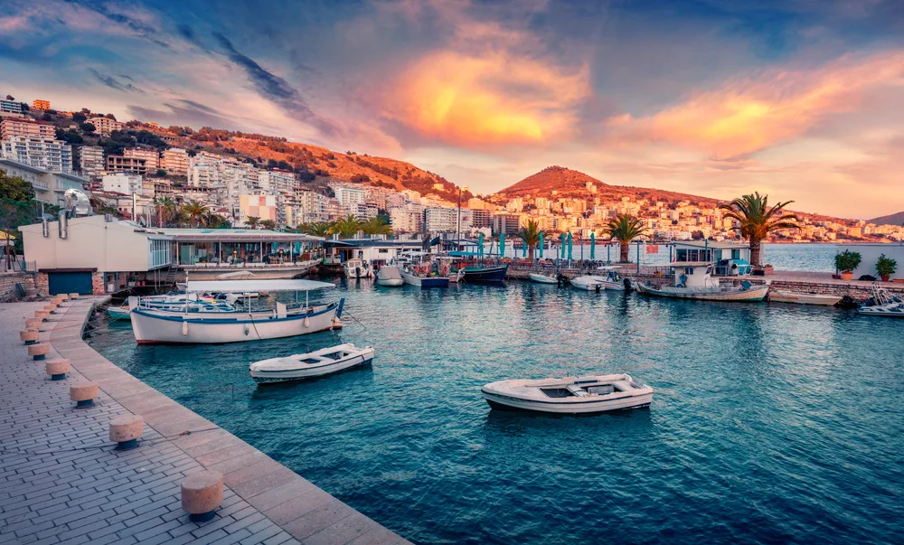 Saranda port in Albania at dusk with boats docked in the water for a list of the top cheap places to visit in Europe