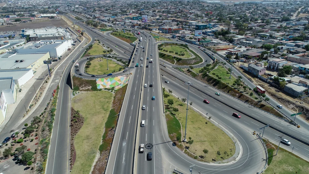 An intricate highway leading towards an urban zone in Rosarito, one of our picks for the best places to stay in Tijuana, the town ahead can be seen populated by various urban structures.