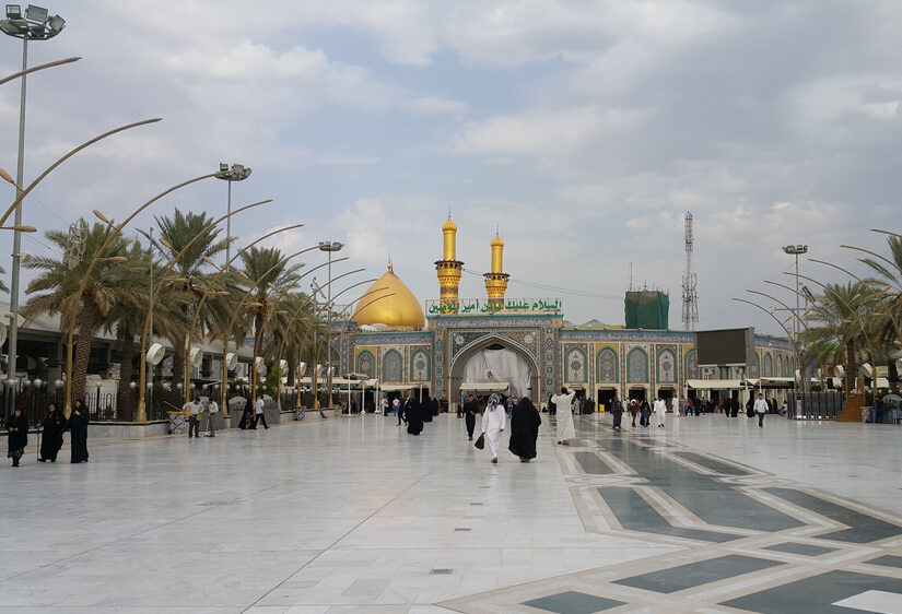Photo of a gorgeous shrine pictured during the least busy time to visit Iraq, featuring several people mulling about