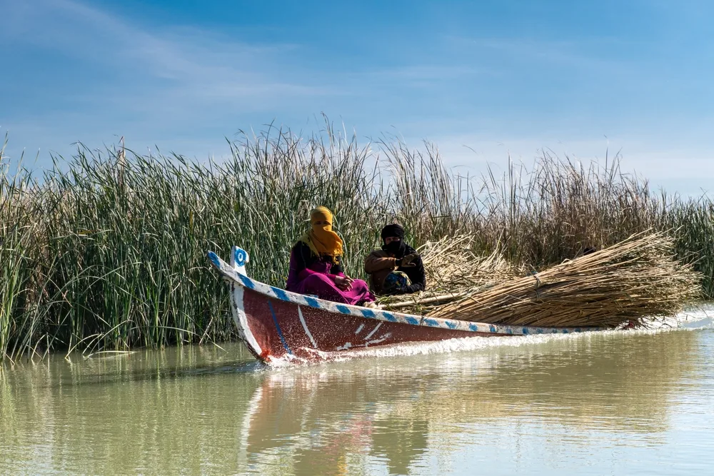 Two people in a boat driving down the river in Chibayish Iraq, pictured during the best time to visit the country