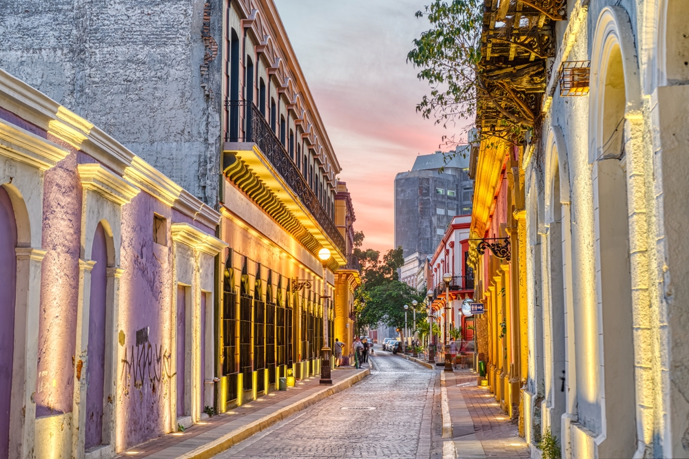A well-lit narrow street at Centro Histórico in Mazatlán, Mexico, where old walls and brick street can be seen during sunset.