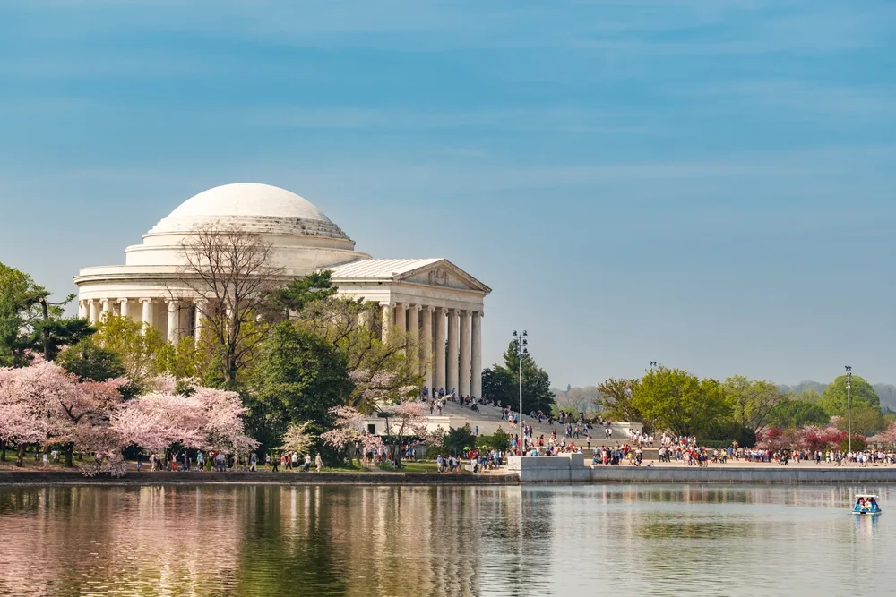 People flocked in the Thomas Jefferson Memorial, and some blooming cherry blossoms are seen on its left side. 