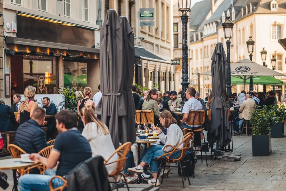 Photo of people enjoying a nice meal on a terrace outside in the summer for a guide titled Is Luxembourg Safe to Visit