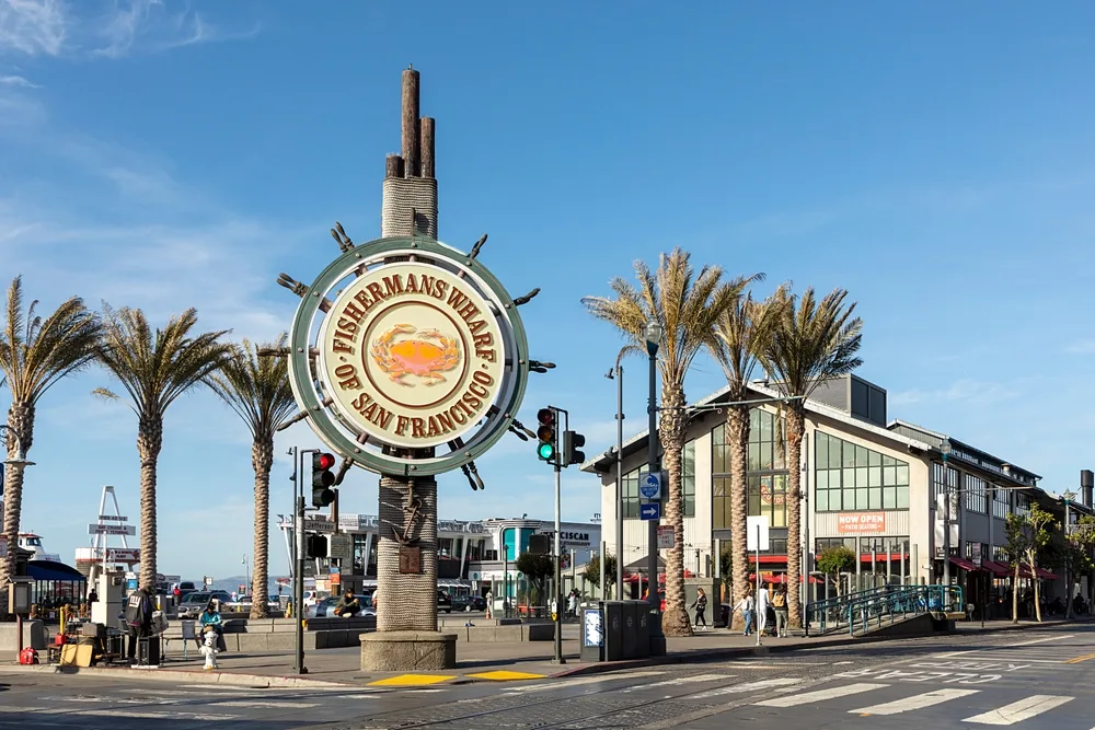 A gigantic ship's wheel served as a landmark that says "Fisherman's Wharf of San Francisco"
