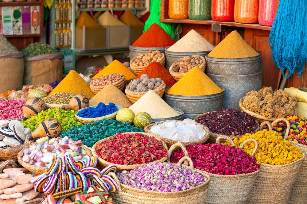 Several basket full of spices with vibrant colors displayed in a storefront. 