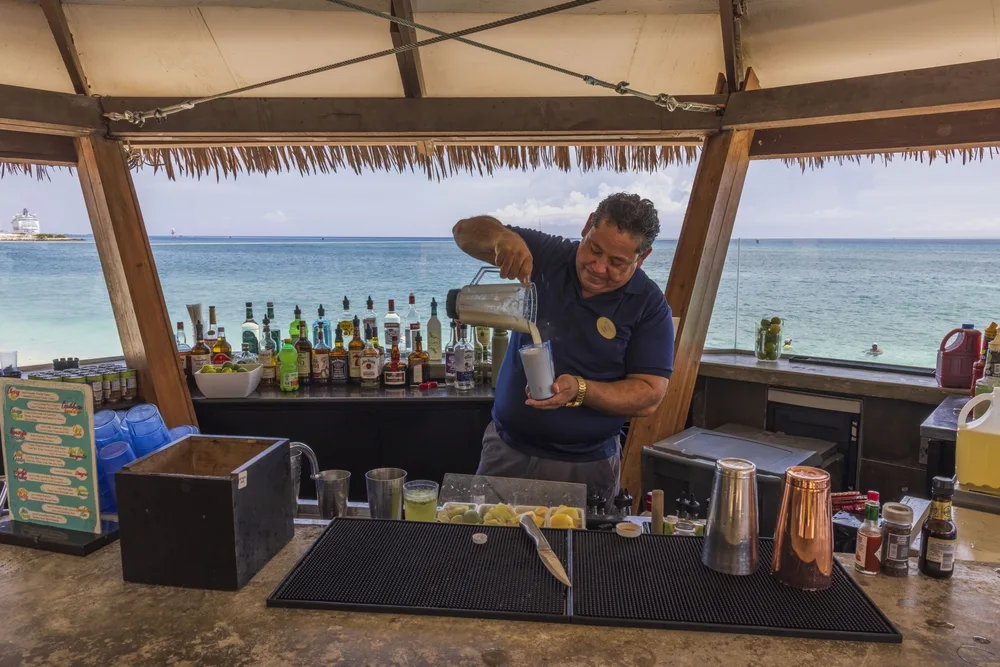 A bartender preparing a drink in a bar beside the beach. 