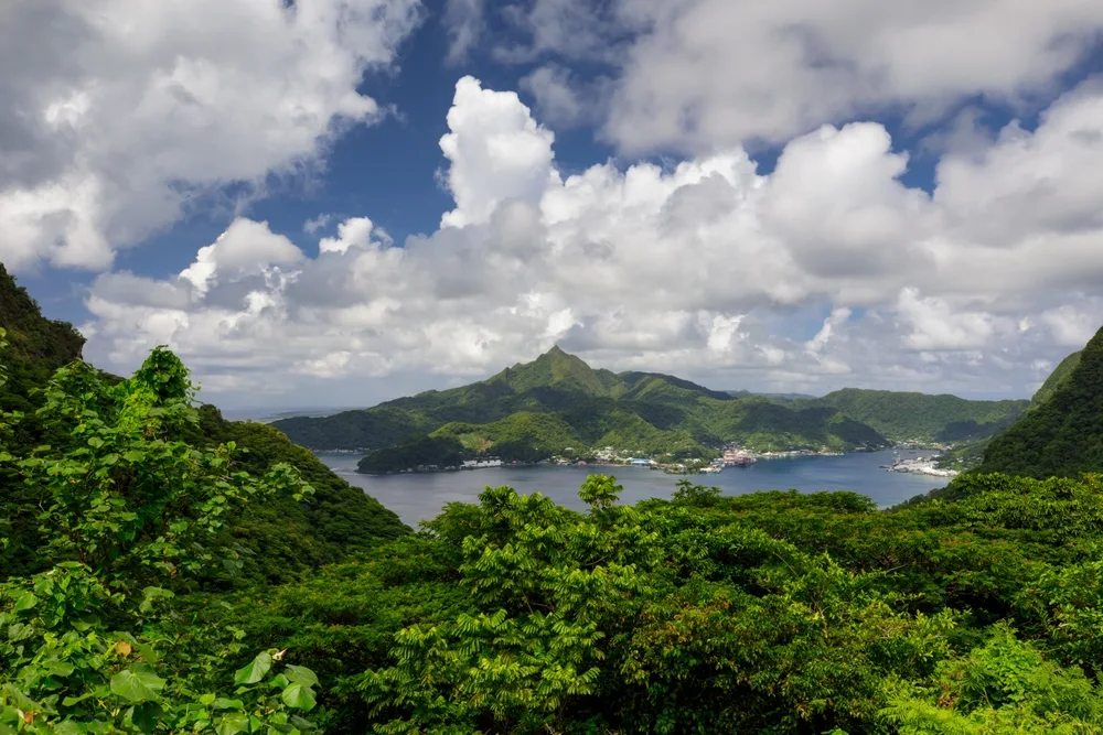 Aerial view of Pago Pago in Tutuila, American Samoa with clouds overhead and green vegetation over the mountains for a list of the top places to travel without a passport
