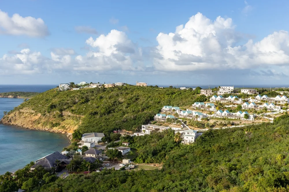 Aerial view on a community with houses surrounded by trees located near a beach in The Valley, one of the best areas to stay in Anguilla.