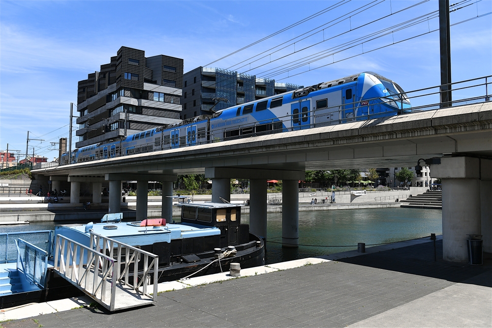 Train making its way over a river on a bridge in the Confluences district in Lyon for a guide on whether or not it's safe to visit the city