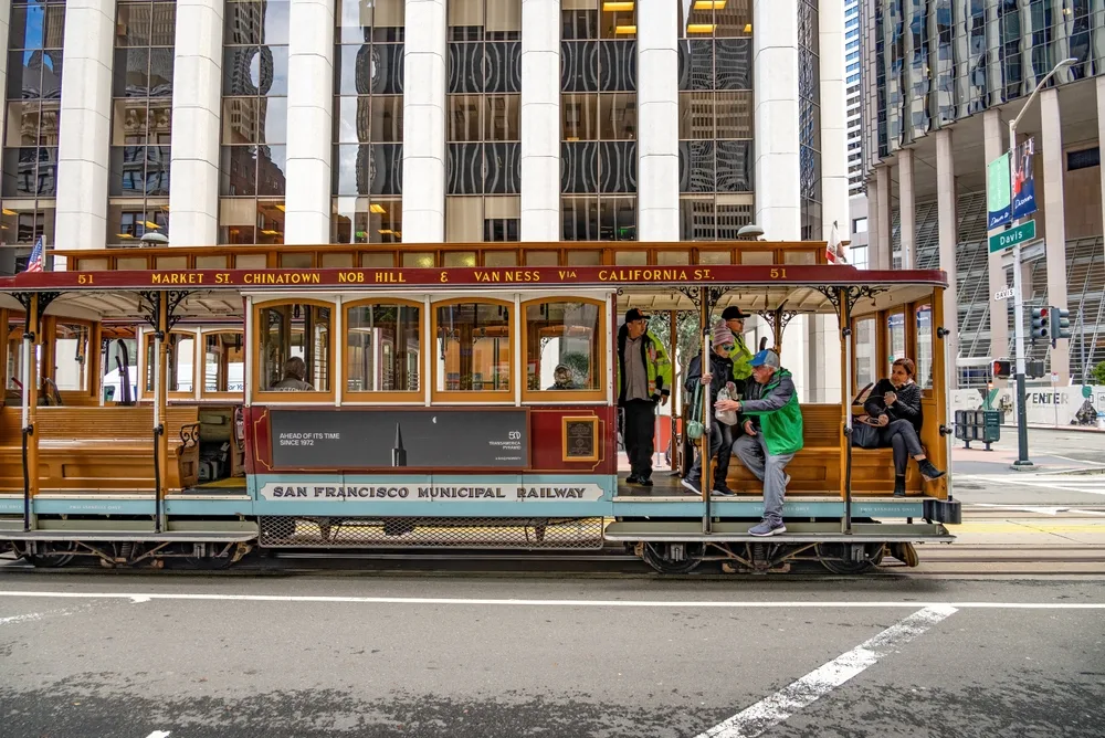 A cable car in that says San Francisco Municipal Railway where operators seat in front. 