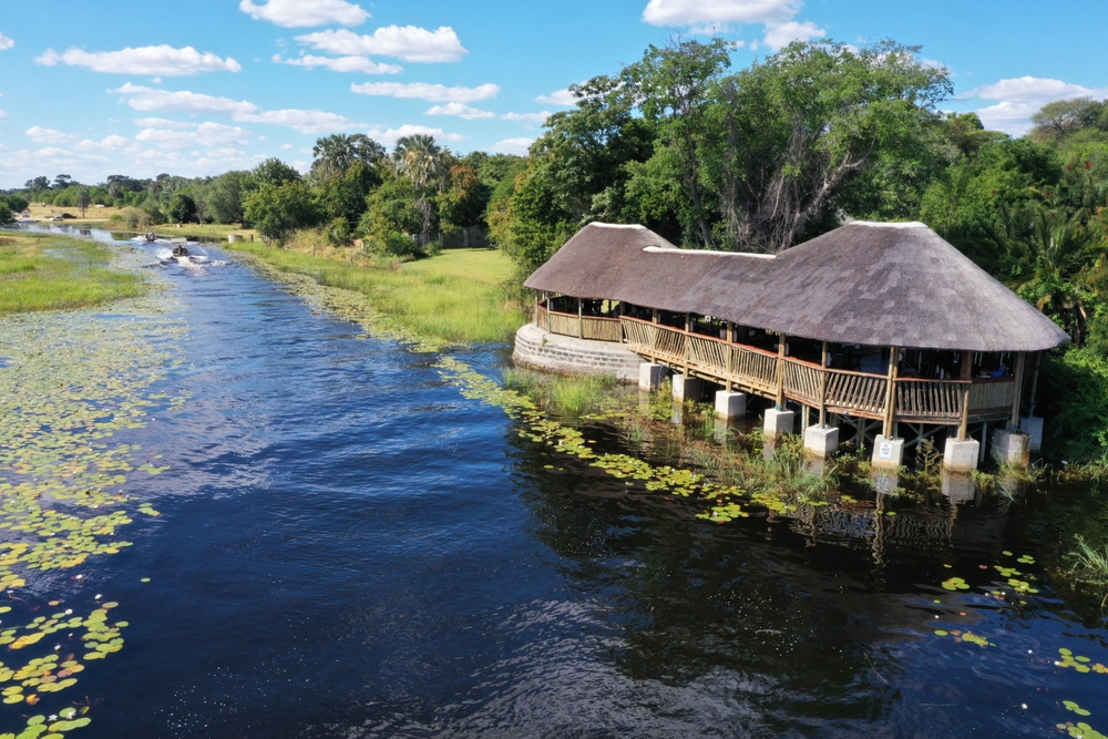 A native hut built on a slowly flowing river with lilies on the side in Maun, one of the best areas to stay in Botswana.