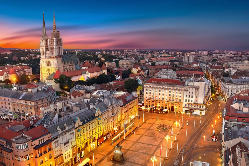 An old city in Zagreb during a sunset, one of the best areas to stay in Croatia, an empty town square is illuminated by street lamps.