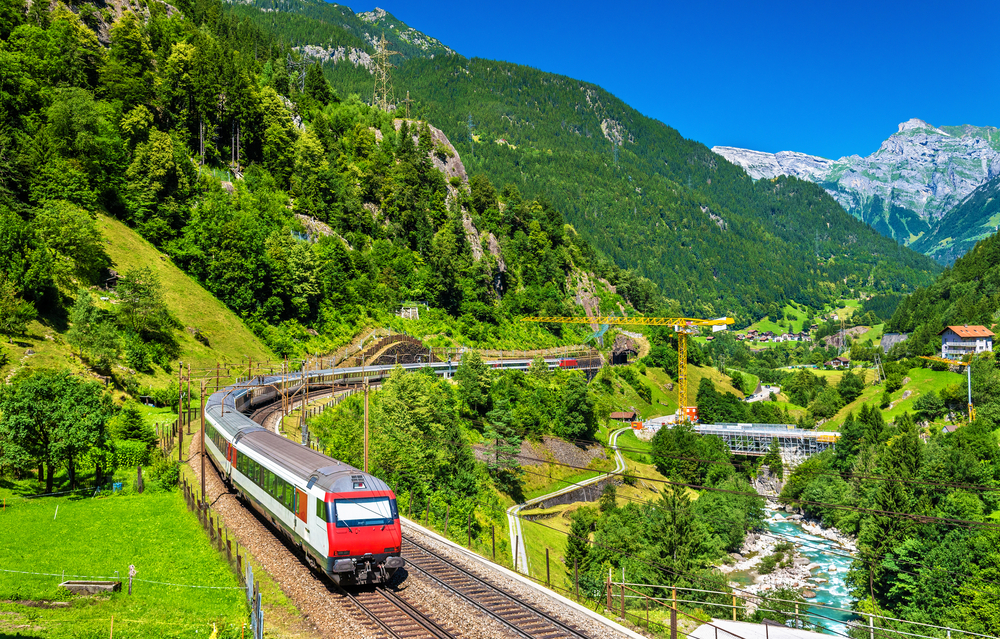 Aerial view of Gotthard Railway passing through an alpine village in Switzerland during summer, one of the top places for solo travelers to go