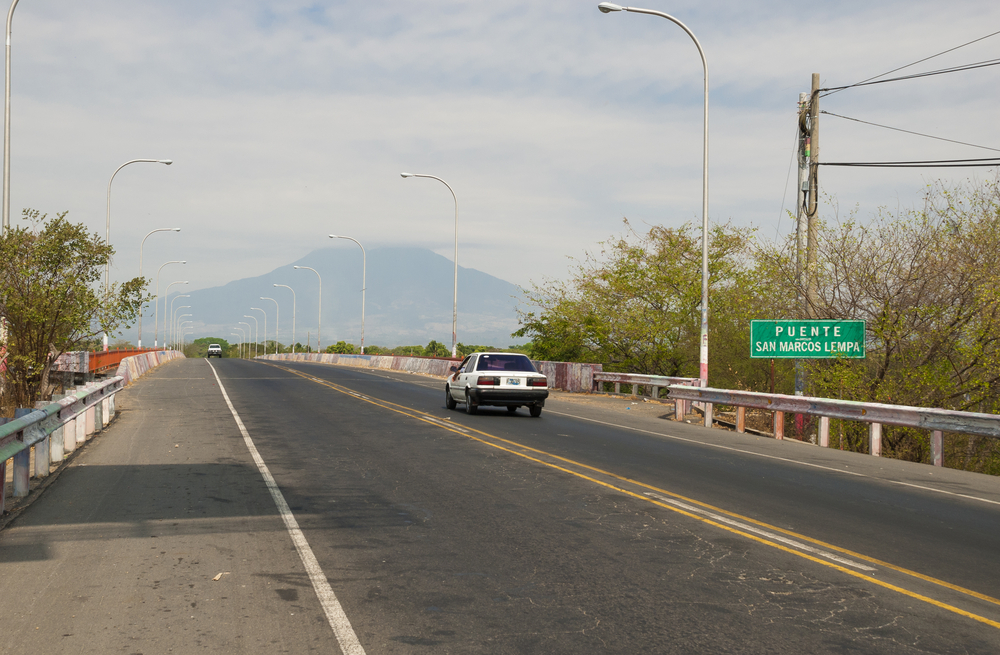 Photo of a lone car driving down the road in San Marcos, pictured for a guide titled Is El Salvador Safe to Visit