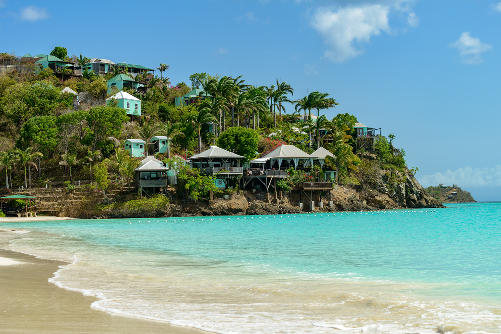 Tropical beach pictured with blue sky above teal blue water for a guide titled Is Antigua Safe to Visit