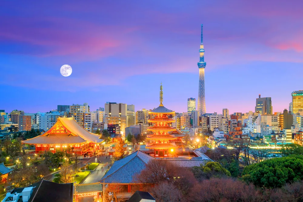 Tokyo skyline with Sense-Ji Temple lit up at night with a full moon overhead to show Japan as one of the best places for solo travel