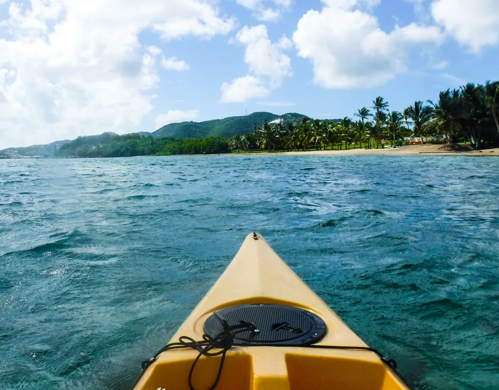 Perspective from person sitting in a yellow kayak facing the shores of St. Croix for a frequently asked questions section on the places to travel without a passport