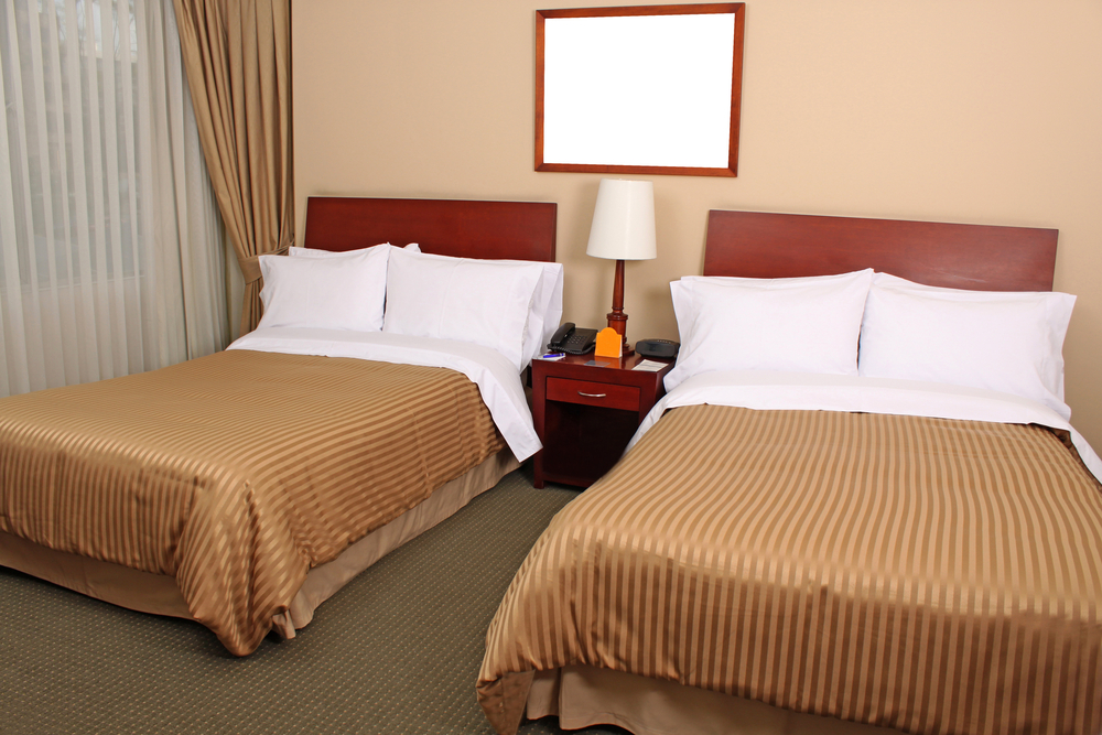 Motel room interior with 2 queen beds and very basic decor highlighting the difference between motel vs hotel vs inn