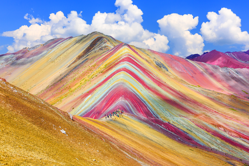 Tourist an be seen walking above a mysterious mountain with different colors.