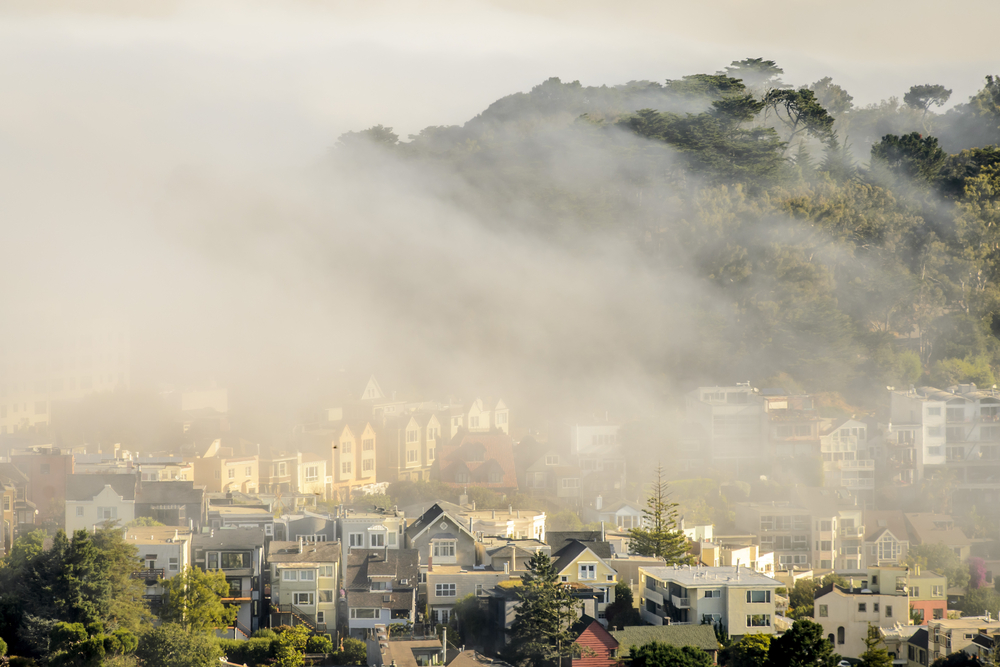 A dense fog settled over San Francisco houses and hills to show what the climate is like in Northern California vs Southern California
