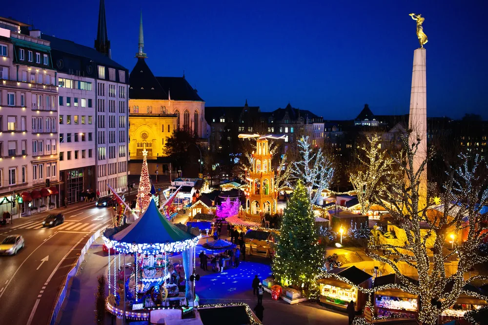Christmas fair in Luxembourg pictured with lights all over buildings and trees and a dark sky above the scene to help answer the question is Luxembourg safe
