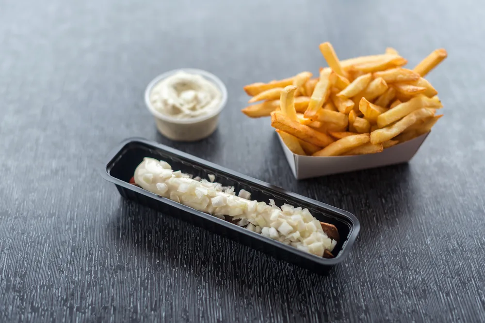 Frikandel with mayonnaise sauce and fries topped with diced onions, among the best Dutch food to try