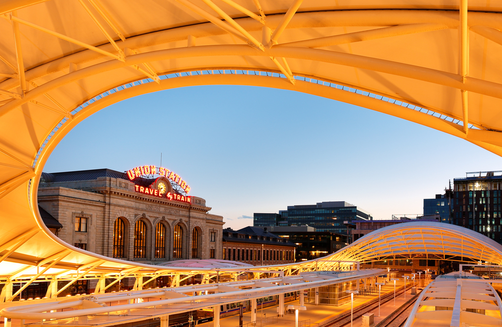 Union Station in Denver pictured for a guide titled Where to Stay in Colorado with its unique honeycomb shade structure in the foreground, pictured at dusk