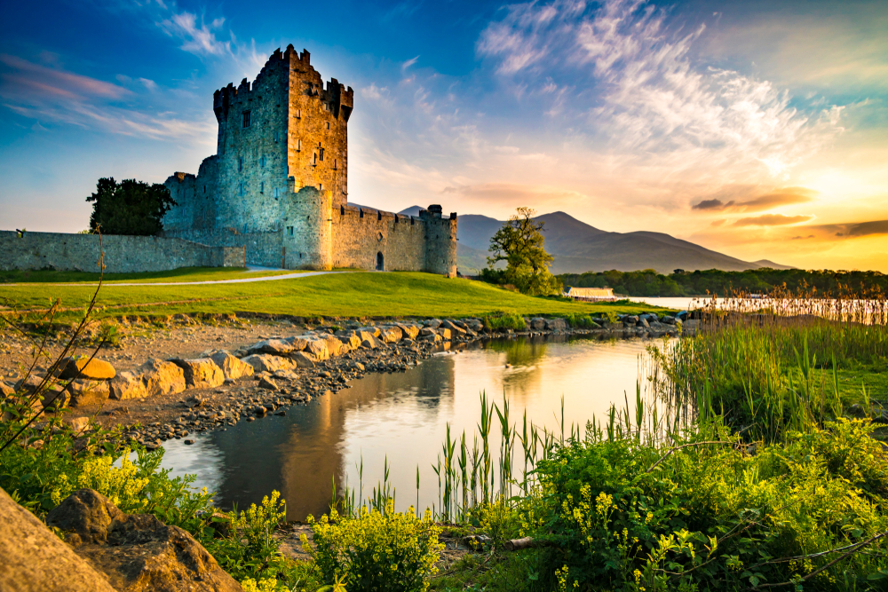 Ancient old Ross Castle in Ireland pictured on a nice summer day with a picturesque sunset over the hills