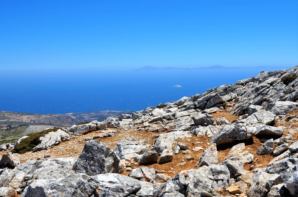 A photograph from the peak of a mountain with a vague view of the opposite island and the sea. 