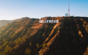 The Hollywood sign at the top of a hill with a tall cell tower.