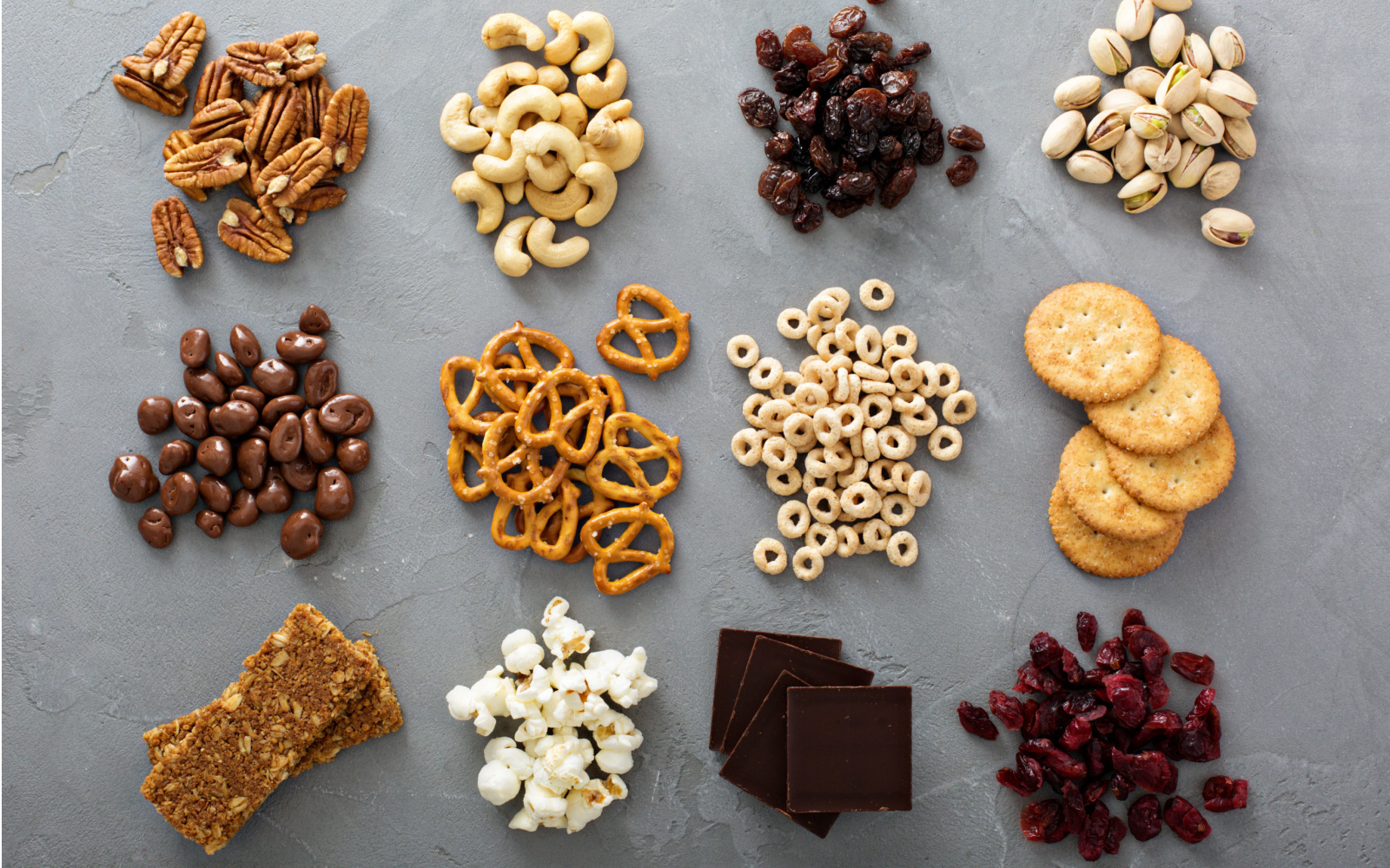 Variety of healthy snack foods in piles on a table for a piece explaining can you bring snacks on a plane