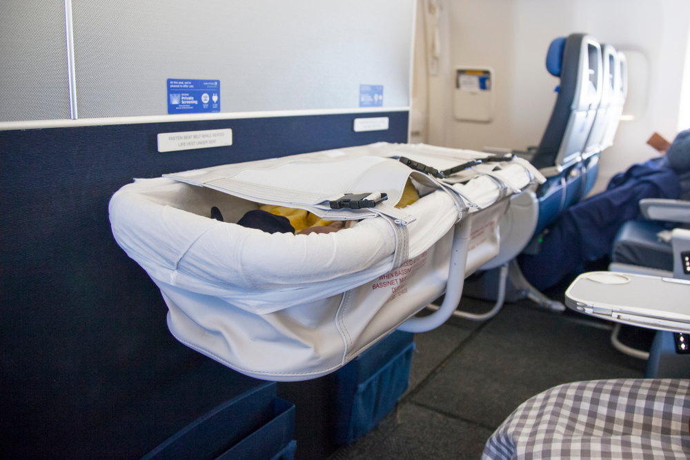 Baby in a bassinet mounted to the bulkhead wall for a section exploring the pros of front row bulkhead seating on a plane