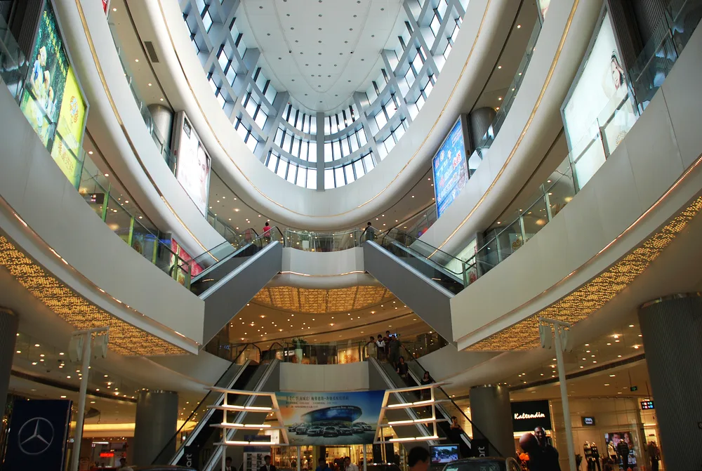 Interior view of a mall with several floors where the top floor can be seen with glass windows.