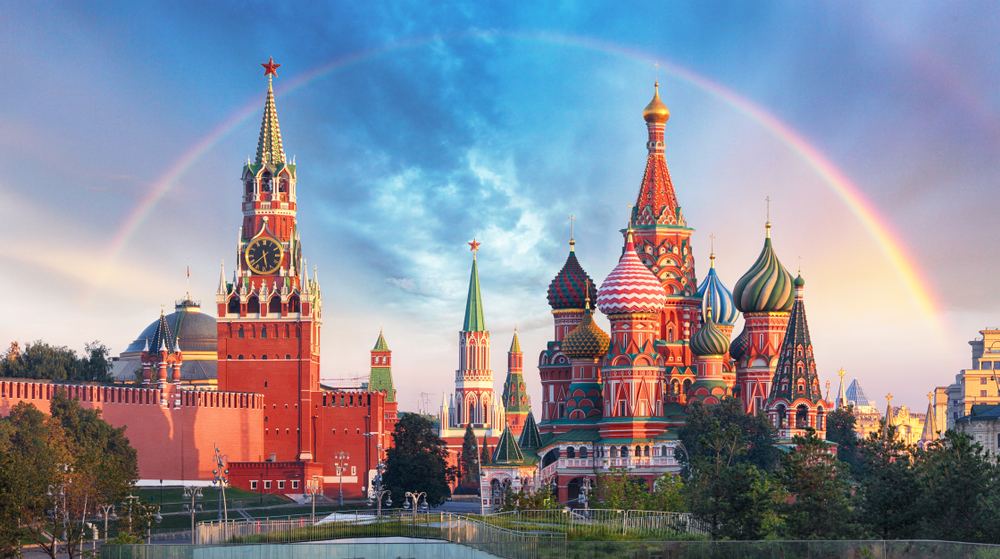 A rainbow can be seen over a castle with vibrant red color and swirling pattern roofs. 