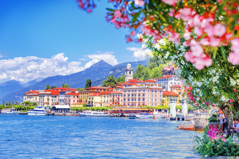 Hotel buildings can be seen located near the lake where some fishing boats are docked on its pier in Bellagio, one of the best places to stay in Lake Como