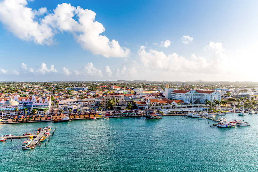 Aerial view of the Oranjestad Marina with fluffy clouds overhead on a sunny day for a piece asking how long is a flight to Aruba with no stops from the US?