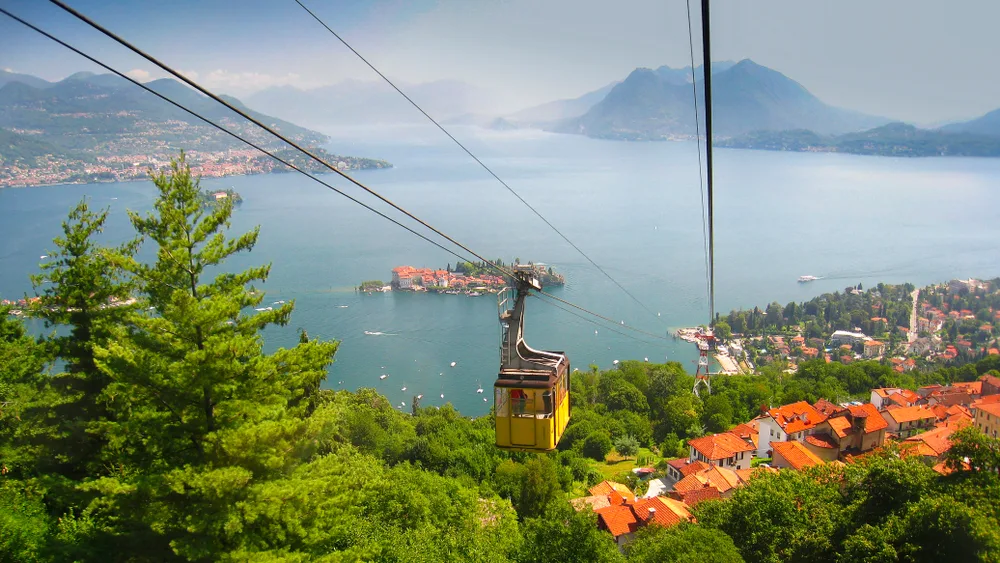 A cable car descending forest slope to a lake town in Stresa, one of our top pick on the best areas to stay in the Italian Lakes, across the lake are other towns and mountains. 