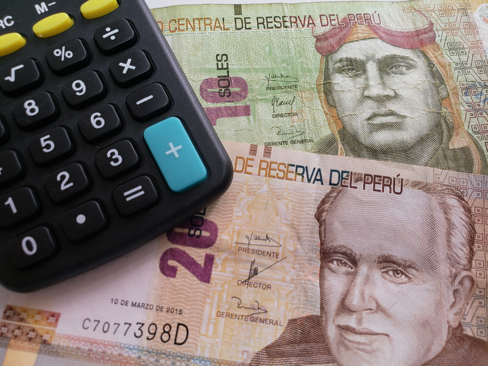 Two Peruvian currency placed under a calculator, a concept to show the economy of Peru, an item on the list of facts about the country.