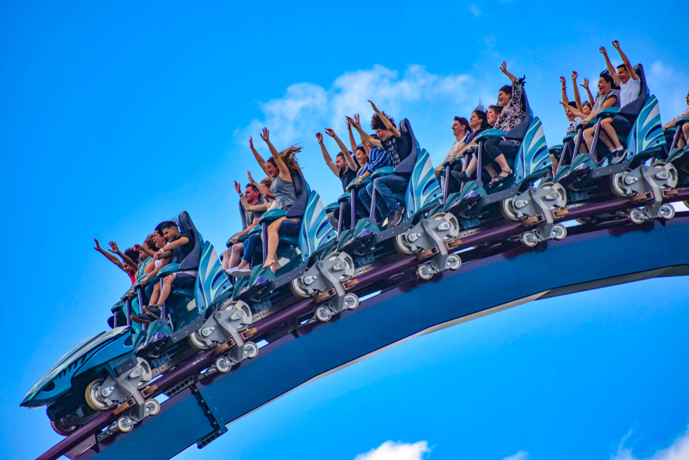 People raising their hands as the roller coaster is going down in an amusement park. 