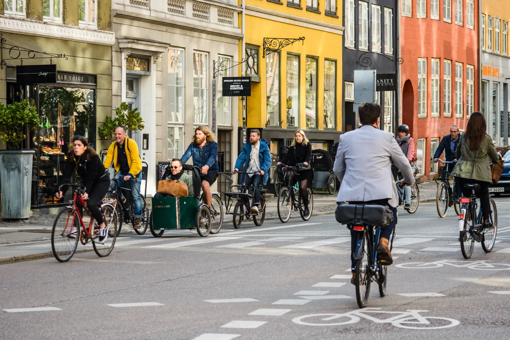 Daily cyclist commuting in a town within the designated bike lane in a street surrounded by city structures. 