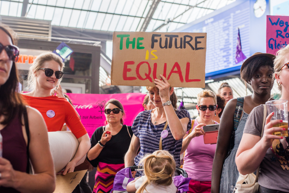 Woman on a strike where one can be seen carrying a signage with text "The Future is Equal."