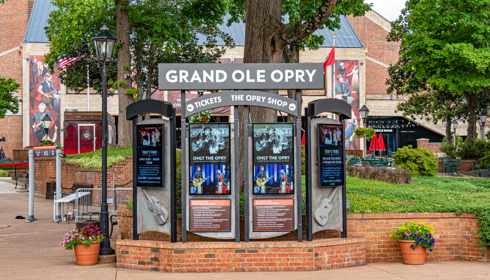 An information board that says "Grand Ole Opry' and it displays pictures of people playing guitars, for a piece on an article about trip cost to Nashville.