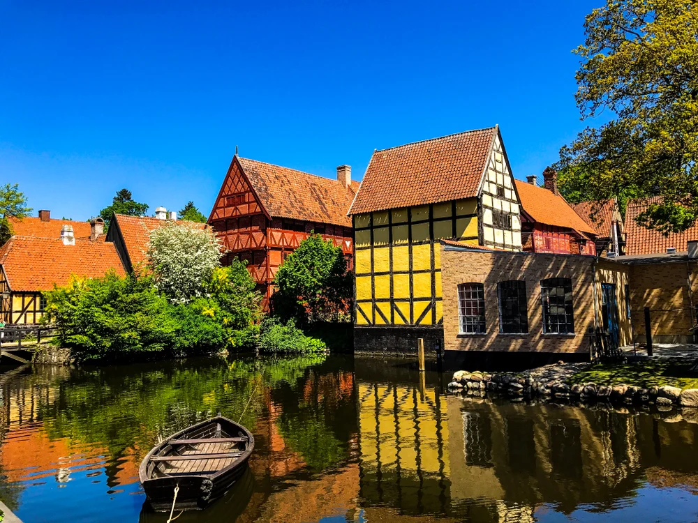 Traditional old houses built beside a river where a moored small boat can be seen.