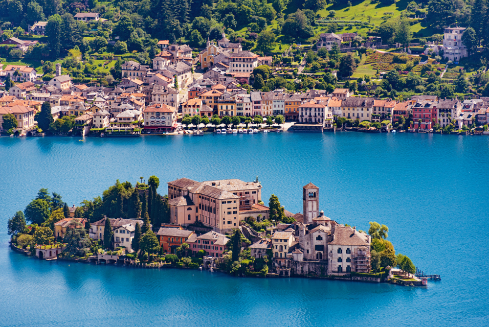 A very small island in Orta San Giulio, one of the best areas to stay in the Italian Lakes, field with structures where some are built on the edge if the island, and close to it is the mainland with several structures, also.
