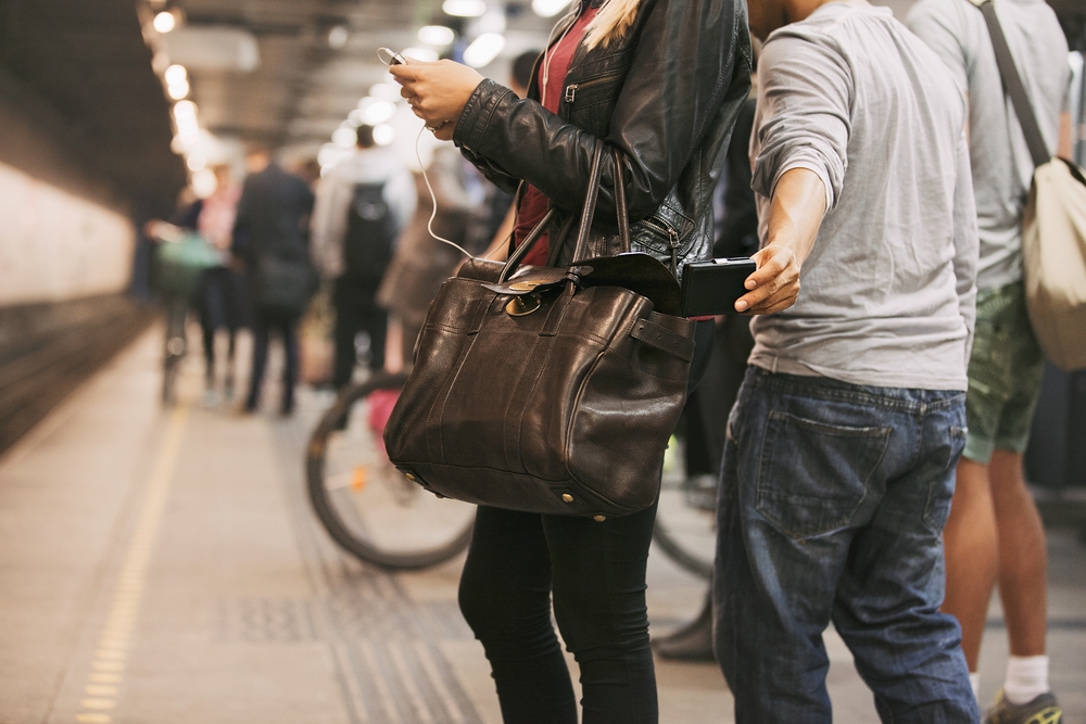 A man pickpocketing on a woman's bag while waiting on a train station, a concept image on the guide about safety in visiting the Netherlands.